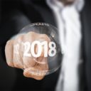 Ein Mann berührt ein Button mit 2018, der im Vordergrund des Bildes zusehen ist