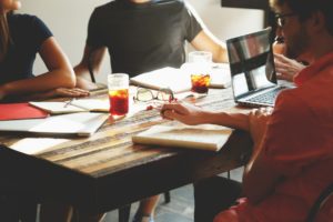 Personen sitzen an einem Tisch und arbeiten