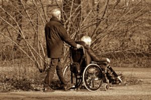 Ein alter Mann schiebt seine Frau im Rollstuhl