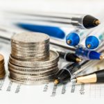 Ein Münzstapel und durcheinander liegende Stifte