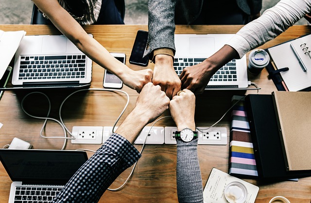 Eine Gruppe von Menschen geben sich in der Mitte des Tischen eine Fistbump